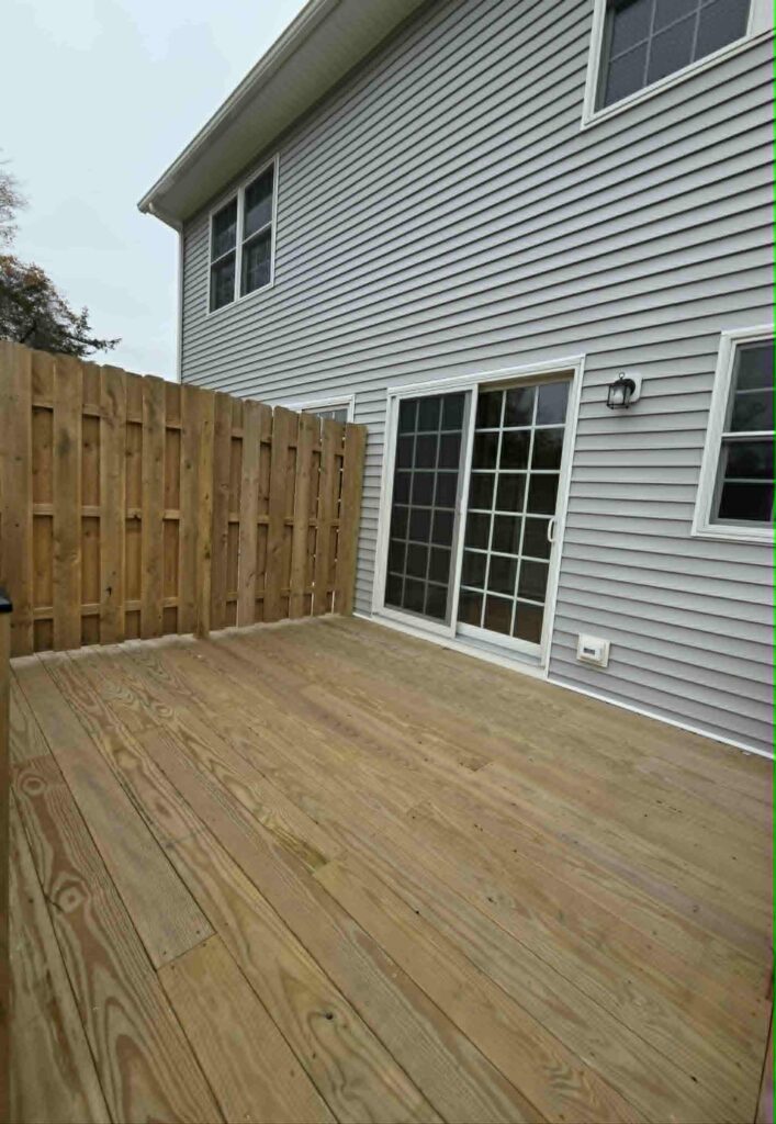 Newly built wooden deck attached to a house with sliding glass doors.