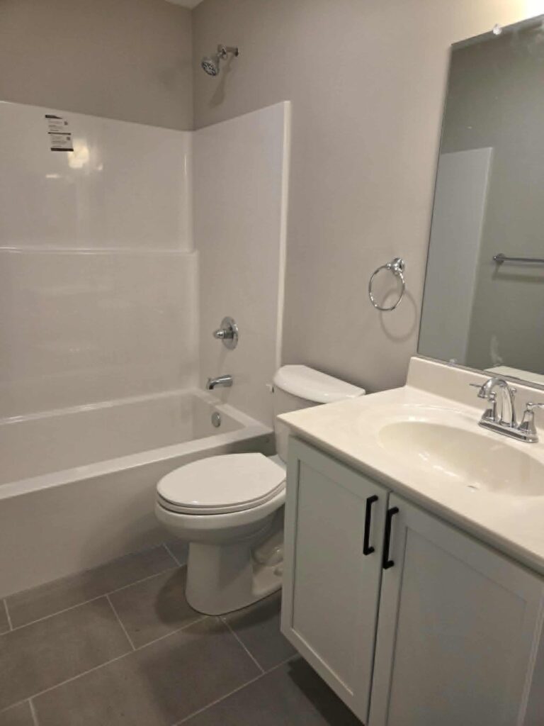 Clean, modern bathroom with bathtub, toilet, and vanity.
