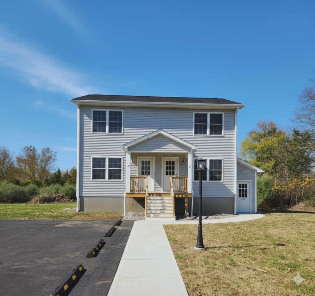 A two-story house with a newly paved driveway and a clear blue sky.