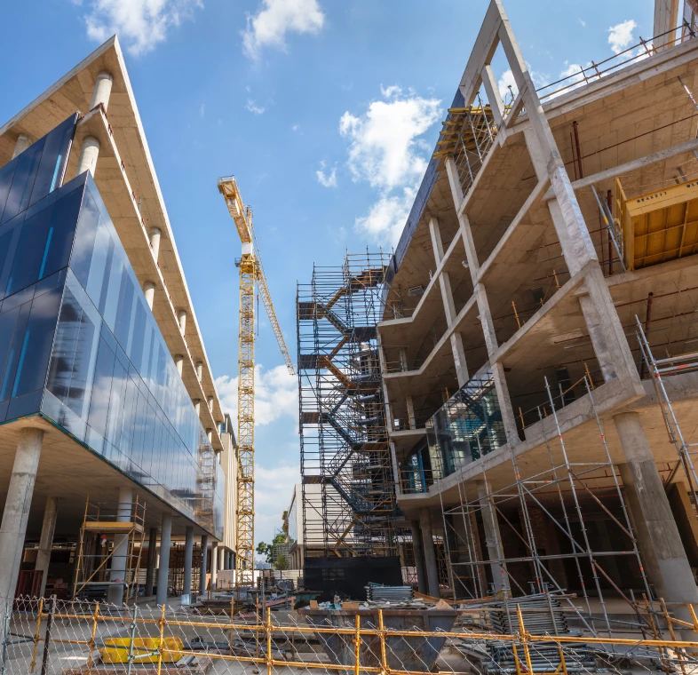 Construction site with cranes and partly built structures under a blue sky.