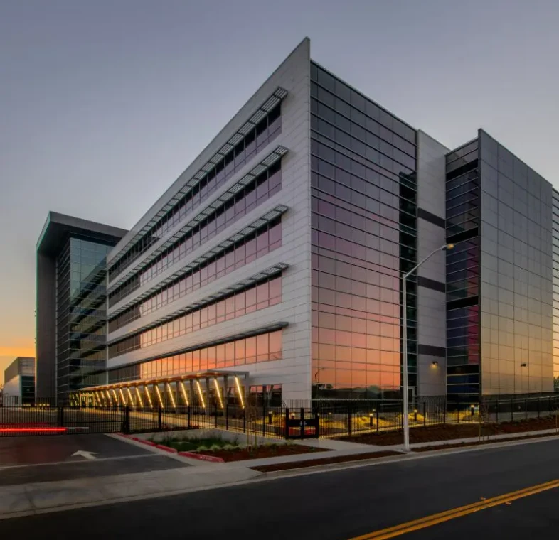 Modern office building with reflective glass at sunset.