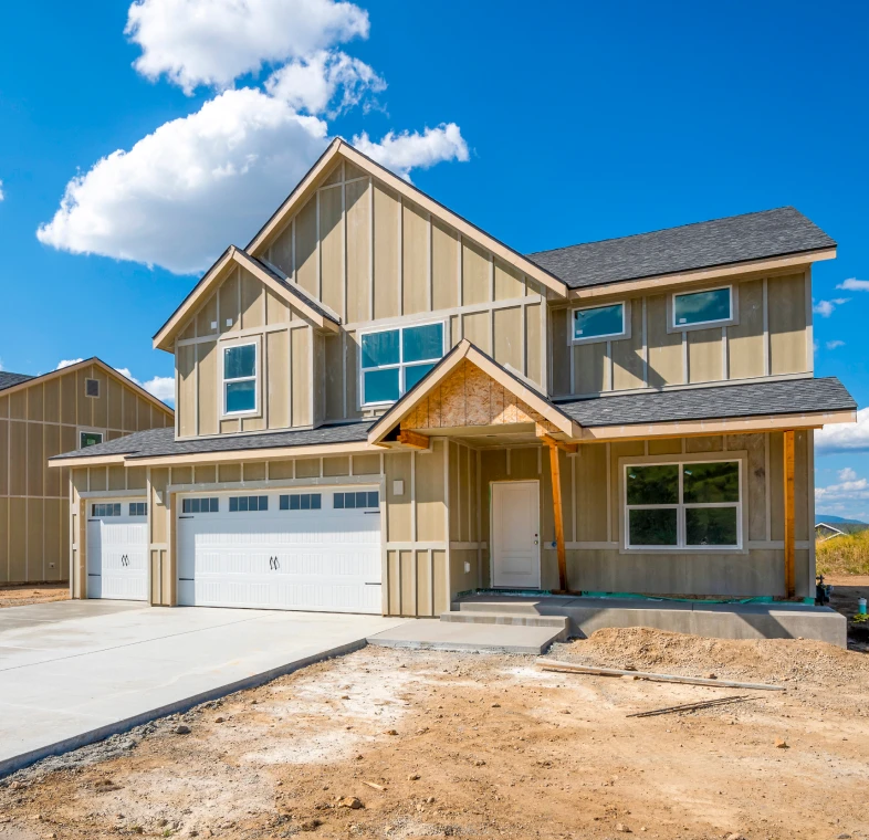 Newly constructed two-story house with beige siding and a three-car garage.