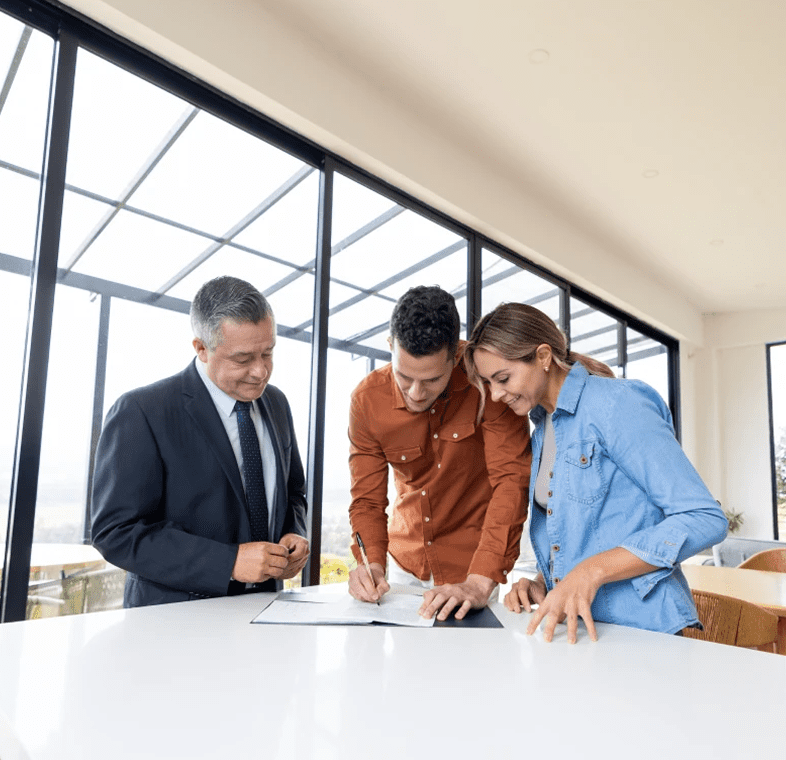 Three professionals reviewing documents in a modern office space.